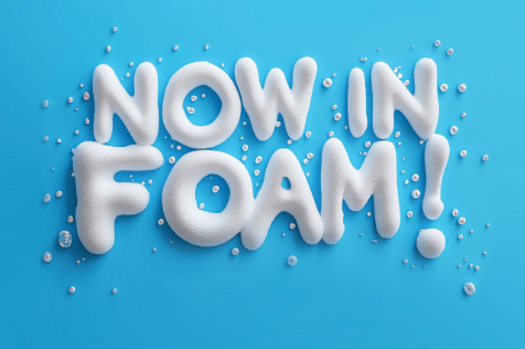3D white foam text reading 'NOW IN FOAM!' with scattered foam droplets on a bright blue background.